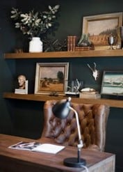antique office with wooden floating shelves and brown upholstered chair