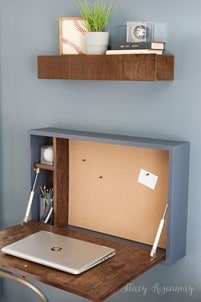 small light blue wall mounted foldable desk with pin board, laptop and small storage compartment