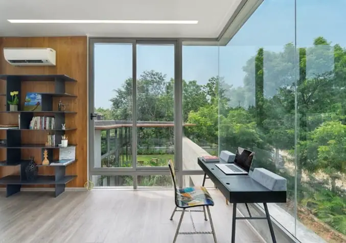 bright and open home office with wide frameless window panels with a garden view