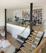 mezzanine home office with wooden staircase and glass railing 